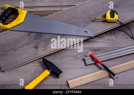 Ausrüstung oder Werkzeuge zum Einbau von Laminatboden, Hammer, Handsäge, Bleistift und Messgerät. Selektiver Fokus. Stockfoto