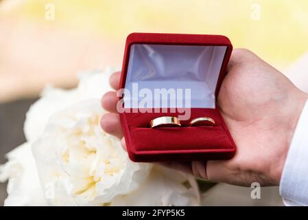 Eheringe in einer Schachtel, die in einer männlichen Hand gehalten wird. Symbol „Ehe“. Vorbereitung auf die Hochzeit. Stockfoto