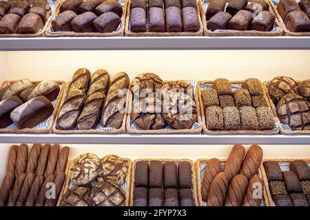 Frisch gebackenes, traditionelles dunkles Brot in einem Bäckerladen. Verschiedene Brotsorten in Backwarenregalen. Stockfoto