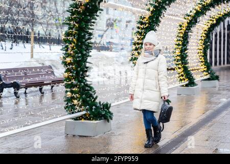 Junge süße blonde Mädchen auf dem Hintergrund eines hellen glühenden Tunnel des Weihnachtsparks. Stockfoto