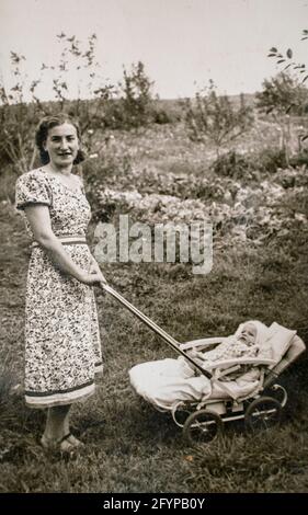 Deutschland - UM 1930er Jahre: Porträt von Mutter und Baby in der Kutsche. Junge Frau und Baby im Kinderwagen. Vintage historischen Archiv Foto Stockfoto