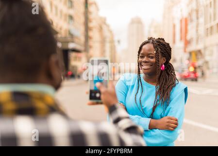 Schwarzer Kerl, der mit seinem Handy ein Foto von seiner Freundin gemacht hat. Stockfoto