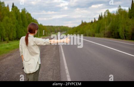 Das Mädchen hält das Auto mit der Hand auf der Autobahn an. Stockfoto