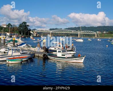 PUERTO PESQUERO EN LA RIA CON BARCAS Y PUENTE DEL FERROCARRIL AL FONDO. Lage: AUSSEN. PUENTEDEUME/PONTEDEUME. A CORUÑA. SPANIEN. Stockfoto