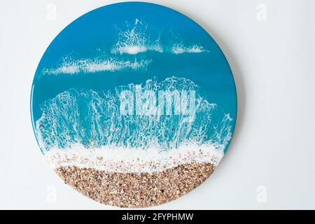 Kunstgemälde aus Harz mit blauen Meereswellen und Strand auf weißem Hintergrund. Epoxidharz Stockfoto