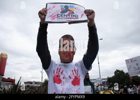 Ein Protestler trägt eine Gesichtsmaske von Präsident Iván Duque und hält ein Schild mit der Aufschrift: „Demonisches Zentrum“ in Bezug auf die kolumbianische politische Partei Centro Democrático an einem neuen Tag der Proteste in Bogotá im Rahmen der einmonatigen Gedenkfeier zum Beginn des nationalen Streiks in Kolumbien gegen die Regierung von Ivan Duque am 28. März 2021. Stockfoto