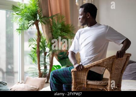 Sportlicher junger afrikanischer Mann, der mit einem Stuhl Yoga praktiziert, Drehstuhl-Pose macht, Parivrtta Utkatasana Stockfoto