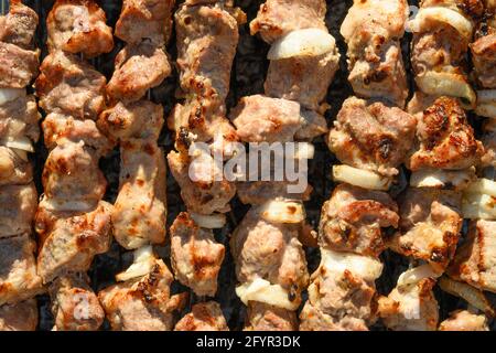 Mariniertes Fleisch Schweinefleisch, das auf einem Grill über Holzkohle zubereitet wird. Grillparty. Lebensmittelmuster. Draufsicht. Stockfoto