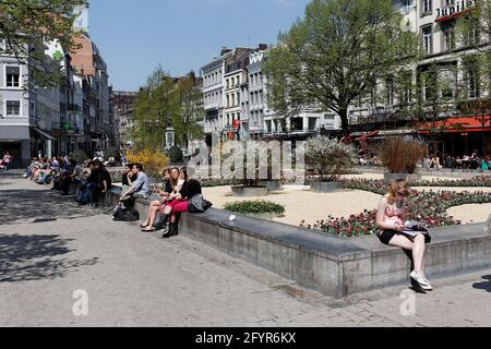 Des touristes sont assis sur un muret Place de la cathédrale à Liège Stockfoto