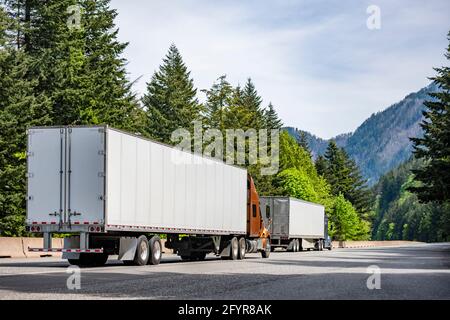 Zwei große Rig-Flurförderzeuge für den Transport von gewerblicher Fracht In verschiedenen Sattelaufliegern, die nebeneinander laufen Richtung auf der Autobahn Stockfoto