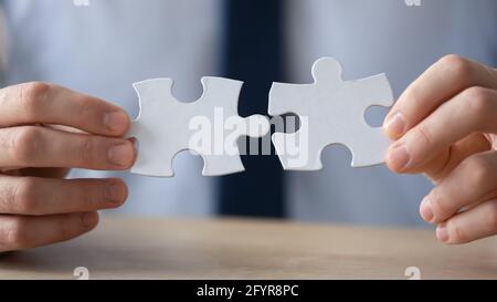 Hände des Geschäftsmannes verbinden zwei Puzzleteile Stockfoto