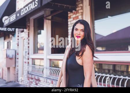 Seriöse Frau, die vor dem Restaurant mit Backsteinwänden steht. Stockfoto