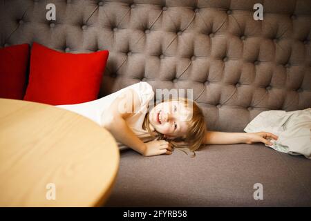 Nettes lächelndes Mädchen, das auf der Couch liegt Stockfoto