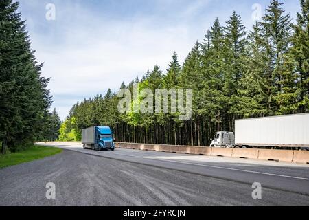 Zwei verschiedene große Rig-Industrie-Sattelschlepper transportieren kommerzielle Ladung in Trockenwagen-Sattelaufliegern, die in entgegengesetzter Richtung laufen Auf der Autobahn r Stockfoto