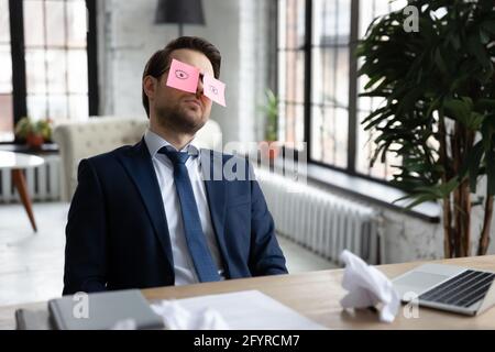 Erschöpft gelangweilt Manager schlafen mit Comic-Papier Notizen auf den Augen Stockfoto