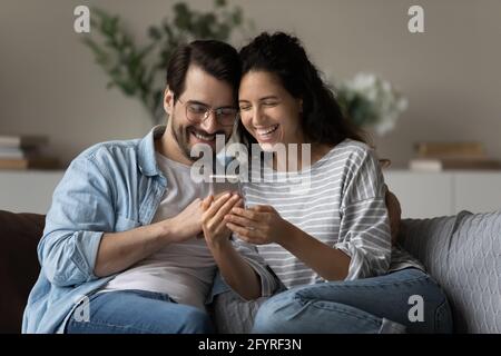 Lächelndes multirassisches Paar hat Spaß mit dem Handy Stockfoto