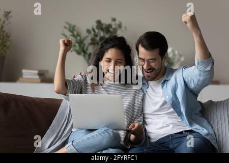 Aufgeregt multirassischen Paar feiern Online-Sieg auf Laptop Stockfoto
