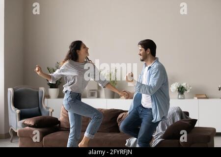 Überfröhliche multirassische Paare tanzen zu Hause zusammen Stockfoto