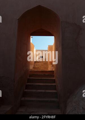 Ein gewölbter, stuckverzierter Eingang mit einer Treppe nach oben. Am alten, alten, restaurierten Fort Nakhal entlang der Rustaq-Route. Im Oman. Stockfoto