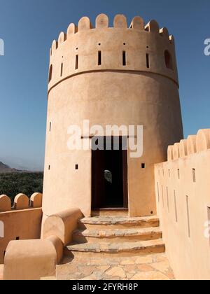 Ein runder, beigefarbener Stuckuhrturm. Am alten, alten, restaurierten Fort Nakhal entlang der Rustaq-Route. Im Oman. Stockfoto