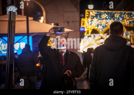 BELGRAD, SERBIEN - 26. DEZEMBER 2020: Selektive Unschärfe bei einem alten älteren Mann, der eine Gesichtsmask mit der Flagge Serbiens trägt und ein Selfie mit seinem Smartpho macht Stockfoto