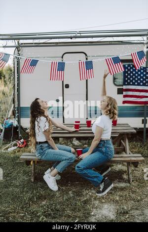 Eine schöne Aufnahme von zwei spanischen Frauen, die ihre Zeit genießen Auf dem Hintergrund der US-Flaggen-US-Unabhängigkeitstag Stockfoto