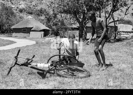 HARRISMITH, SÜDAFRIKA - 05. Jan 2021: Harrismith, Südafrika - 18 2012. Oktober: Afrikanische Kinder, die eine Punktion auf einem Fahrrad reparieren Stockfoto