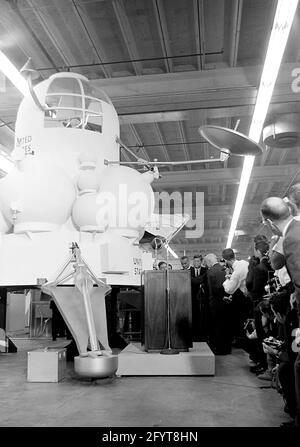 12. September 1962Präsident John F. Kennedy (auf dem Rednerpult) gibt nach einer Führung durch Raumfahrzeuge in einem Hangar im Rich Building des bemannten Raumschiffszentrums, Houston, Texas, eine Rede ab. Präsident Kennedy hält ein maßstabsgetreues Modell des Apollo-Kommandomoduls, das ihm der Direktor des bemannten Raumschiffszentrums, Dr. Robert Gilruth, präsentiert hat; im Hintergrund sitzt ein Modell des Mondlanders (auch bekannt als „der Bug“). Im Hintergrund: Administrator der National Aeronautics and Space Administration (NASA), Dr. James E. Webb; Gouverneur von Texas, Price Daniel; Director of Operations für PR Stockfoto