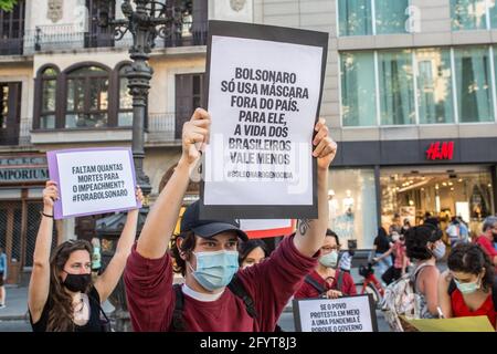 Barcelona, Spanien. Mai 2021. Ein Protestler mit einem Plakat, auf dem steht, dass Bolsonaro nur außerhalb des Landes eine Schutzmaske trägt, während der Demonstration ist das Leben der Brasilianer weniger wert.an dem Tag, der von Demonstrationen in den wichtigsten Städten Brasiliens gegen den brasilianischen Präsidenten Jair Bolsonaro geprägt ist. Brasilianer in Barcelona haben auf den Ramblas von Barcelona protestiert, um sich den Protesten ihres Heimatlandes anzuschließen. Kredit: SOPA Images Limited/Alamy Live Nachrichten Stockfoto