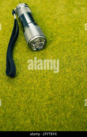 Eine graue und schwarze Taschenlampe auf einer grünen Grasfläche Stockfoto