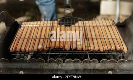 Die Nahaufnahme der Hot Dog Würstchen wird in einem Gitter auf dem Grill gebraten. Stockfoto