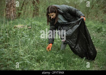 Ein Mädchen mit einem Müllbeutel reinigt die Umwelt von Müll Kopierplatz. Stockfoto