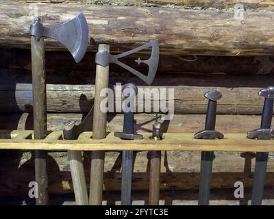 Waffe des alten Ritterschwertes, Äxte stehen auf dem Hintergrund einer Holzwand Stockfoto