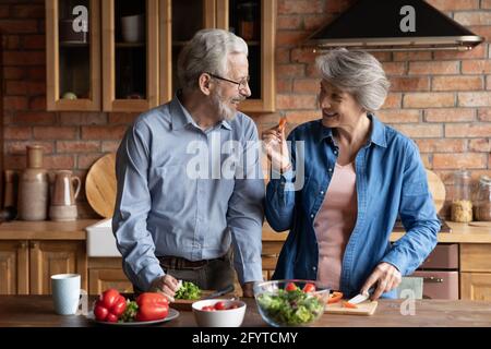 Ein älteres Paar kocht zusammen gesundes Essen in einer modernen Küche Stockfoto