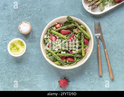 Ein gesunder und köstlicher Salat aus frischen Erdbeeren, grünem Spargel, Feta-Käse mit Gemüseblättern. Stockfoto