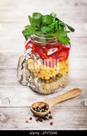 Hausgemachter gesunder Schichtsalat in Maurergläsern auf Holzgrund. Gesundes Leben, Essen, Entgiftung Konzept Stockfoto