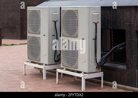 Zwei doppelt kondensierende Einheiten der Klimaanlage im Erdgeschoss in der Nähe der Granitbauwand. Stockfoto