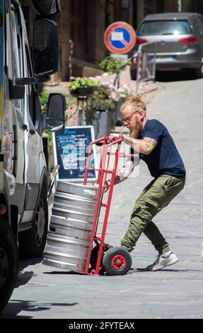 Arezzo, Toskana, Italien, 28. Mai 2021, Junger Mann in seiner Arbeit, der in einer alten Stadtstraße Waren lieferte Stockfoto