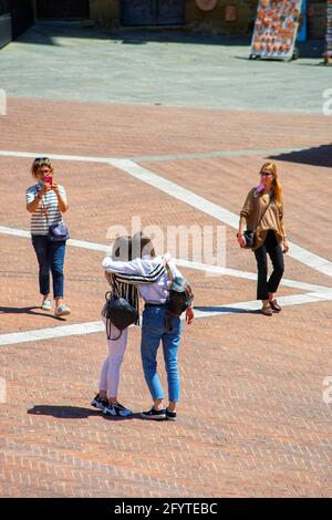 Arezzo, Italien, 28. Mai 2021, zwei italienische Mädchen fragen eine vorbeifahrende Dame um ein Foto auf einem Hauptplatz des Zentrums Stockfoto