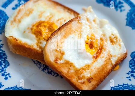 Eierbrot auf dem Teller, fotografiert mit natürlichem Licht. Golden French Toast mit Butter und Ei. Frühstück mit Brot. Englisches Frühstück. Gesundes Frühstück Stockfoto