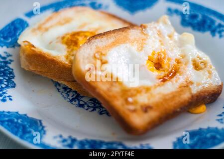 Eierbrot auf dem Teller, fotografiert mit natürlichem Licht. Golden French Toast mit Butter und Ei. Frühstück mit Brot. Englisches Frühstück. Gesundes Frühstück Stockfoto