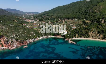 Luftdrohnen-Ansichten über eine felsige Küste, kristallklares ägäisches Meer, touristische Strände und viel Grün an einem wolkenlosen Tag in Skopelos isla Stockfoto