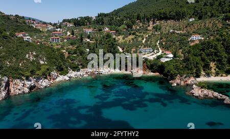 Luftdrohnen-Ansichten über eine felsige Küste, kristallklares ägäisches Meer, touristische Strände und viel Grün an einem wolkenlosen Tag in Skopelos isla Stockfoto