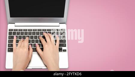 Draufsicht Bild von perfekten weiblichen Händen tippen auf ein Laptop auf einem rosa Hintergrund mit Kopierplatz Stockfoto
