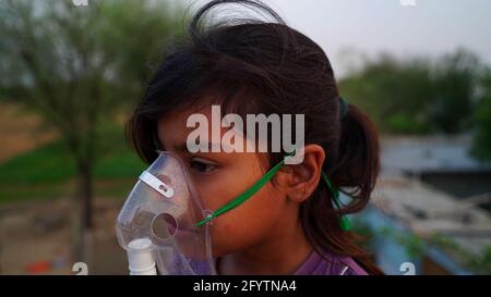 Ein kleines Baby atmet mit Sauerstoffmaske zu Hause. Indian Girl Patient infiziert mit Covid 19 Krankheit.Frau, die Behandlung von Asthma, Lungen. Stockfoto