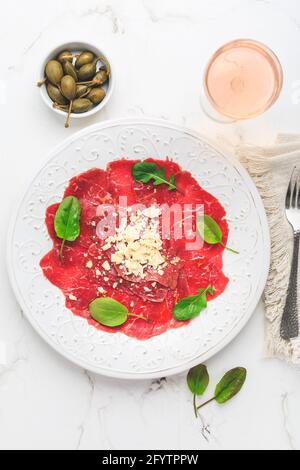 Rindercarpacio mit Kapern und Parmesan als Vorspeise dazu Rosenwein Stockfoto