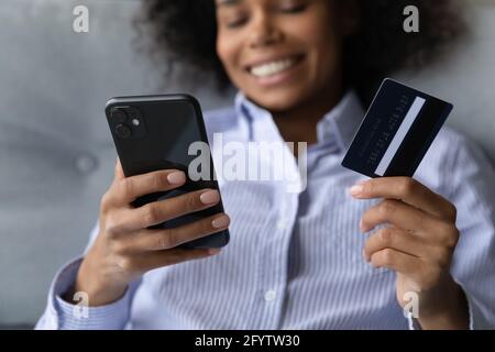Lächelnde Birazialfrau, die online auf dem Smartphone einkauft Stockfoto