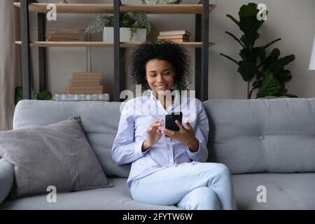 Glückliche afroamerikanische Frau verwenden Smartphone zu Hause entspannen Stockfoto