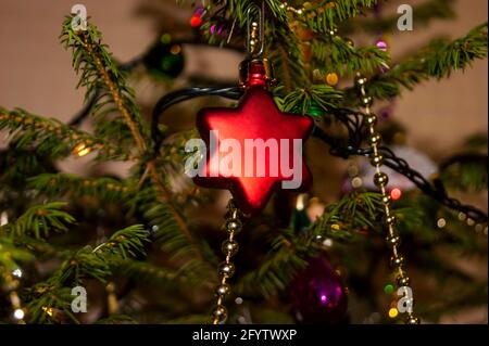 Silvester oder Weihnachten lebhaft elegant dekoriert FichtenNahaufnahme - Weihnachtsspielzeug vor dem Hintergrund von grünen Ästen und Lichtern. Stockfoto