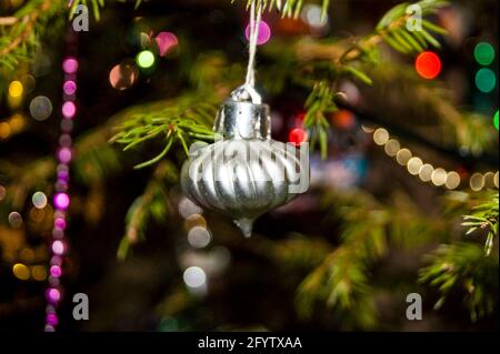 Silvester oder Weihnachten lebhaft elegant dekoriert FichtenNahaufnahme - Weihnachtsspielzeug vor dem Hintergrund von grünen Ästen und Lichtern. Stockfoto